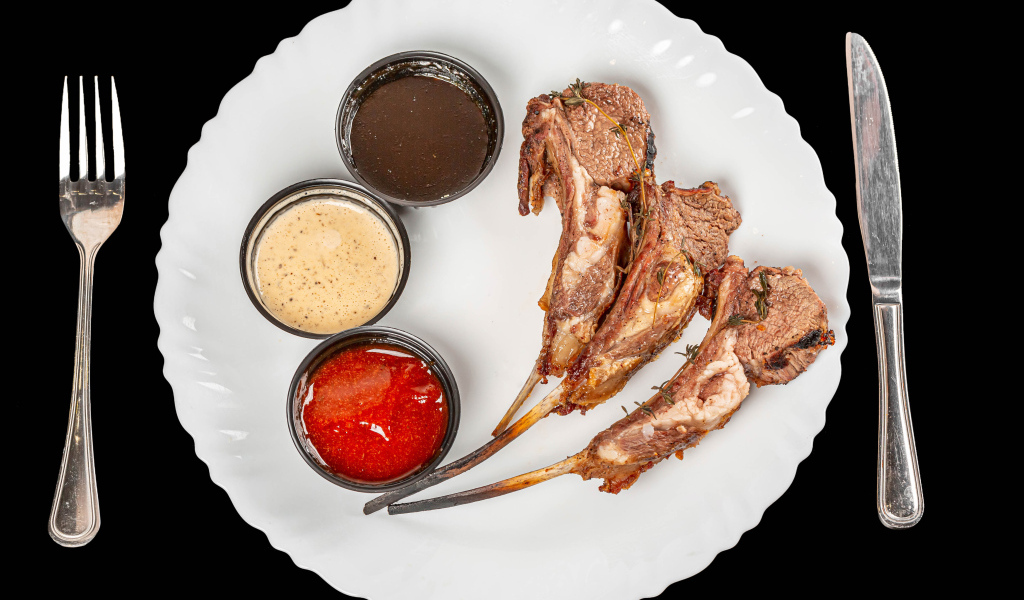 Свиные ребра с соусом на белой тарелке 