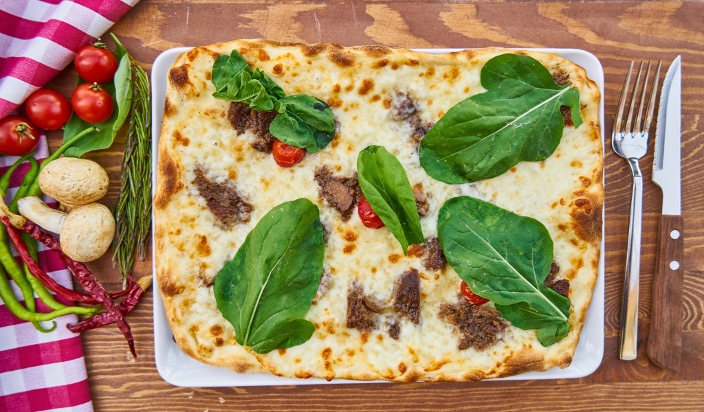 Мясная пицца с сыром и зелеными листьями