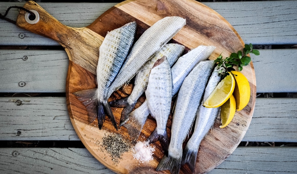 Свежая рыба на доске  с кусочками лимона
