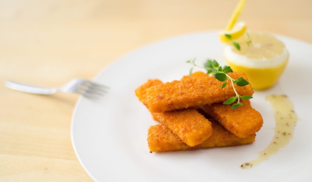 Жареные рыбные палочки на тарелке с лимоном