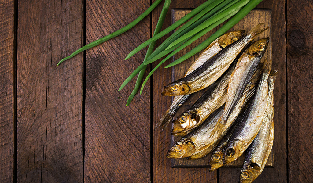 Рыба салака на столе с зеленым луком