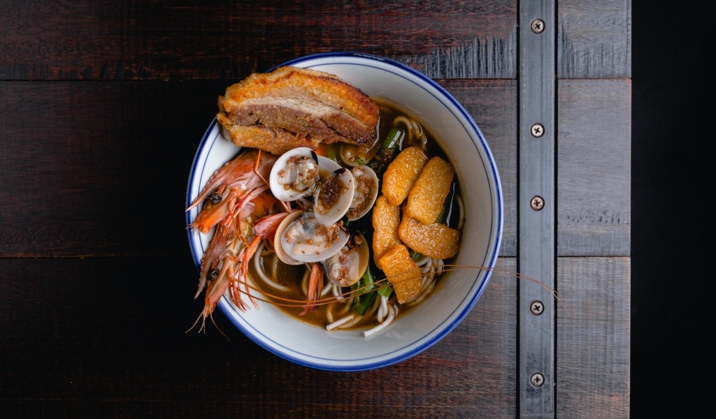 Суп с лапшой и морепродуктами на деревянном столе