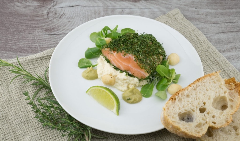 Кусок рыбы с зеленью на столе с хлебом