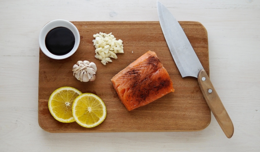 Кусок красной рыбы на доске с лимоном и чесноком