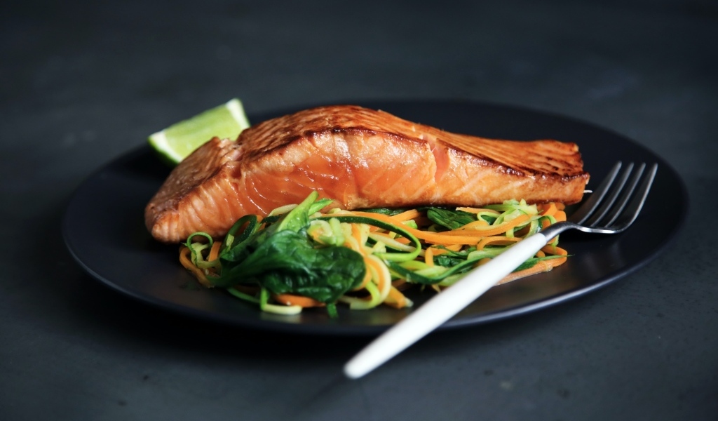 Кусок красной рыбы с салатом на тарелке