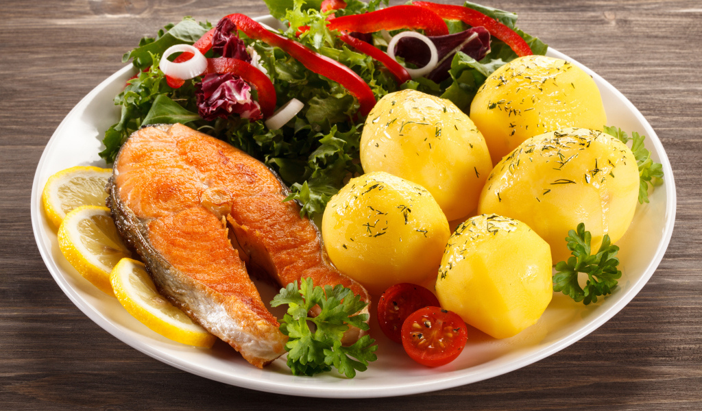 Картофель с кусочками рыбы и зеленью на тарелке