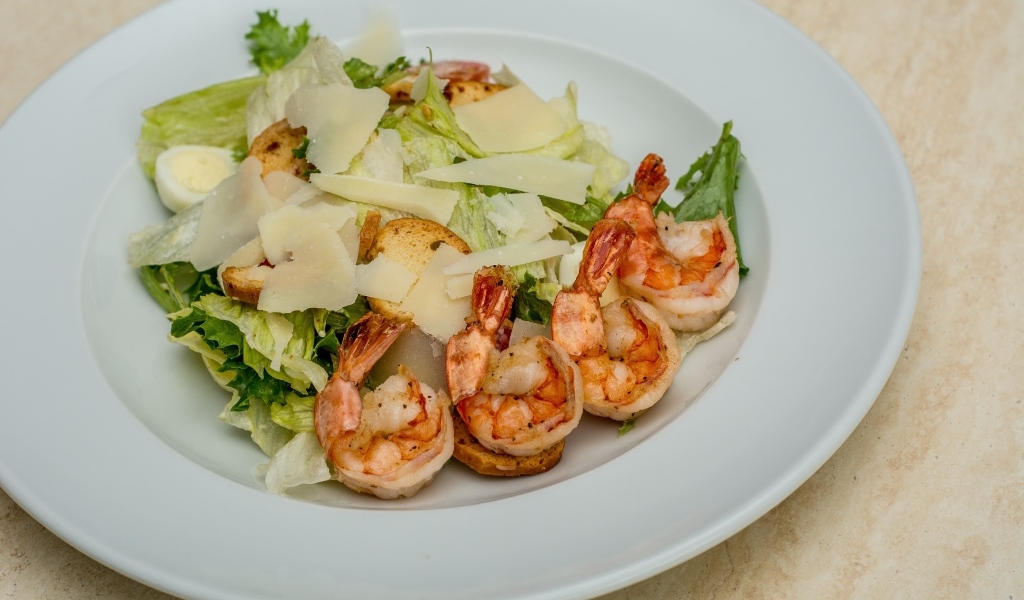 Креветки на тарелке с листьями салата