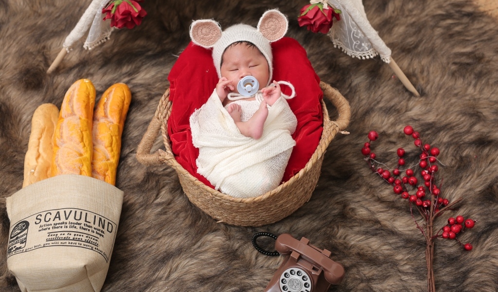 Ребенок спит в корзине с соской во рту