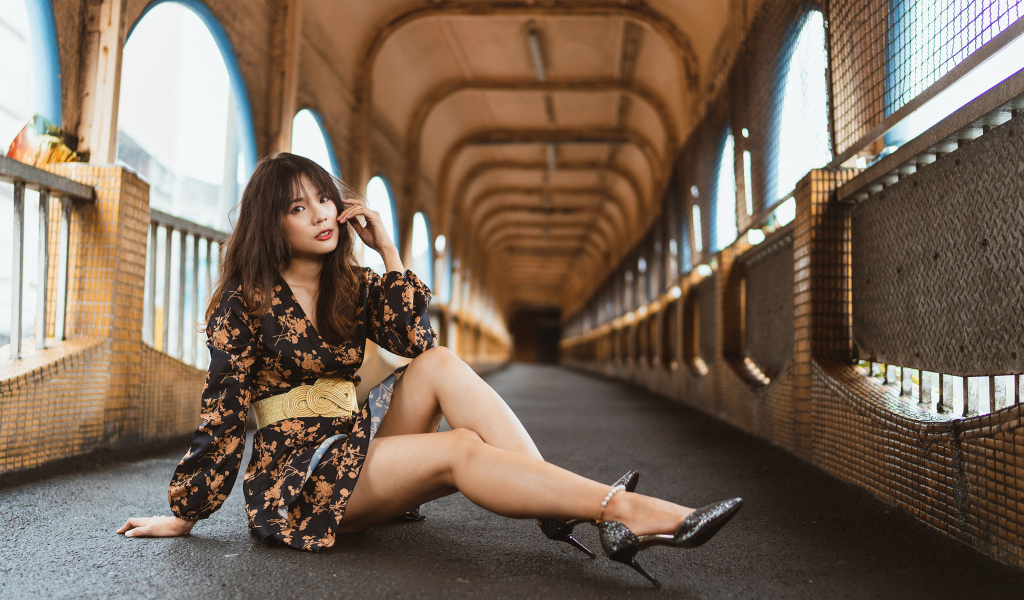 Девушка в красивом коротком платье сидит на полу