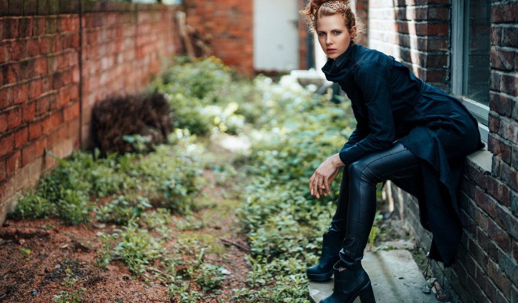 Девушка в черном наряде сидит на окне