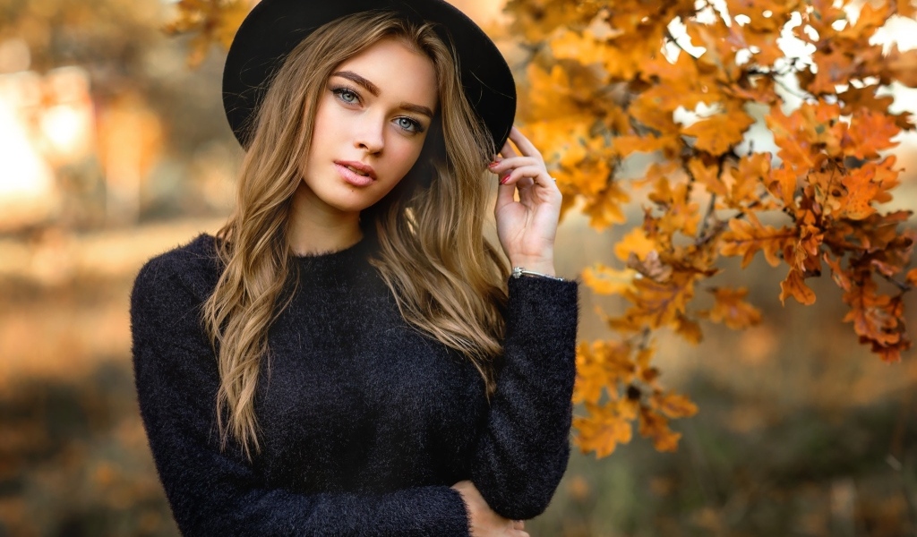 Девушка в черной шляпе стоит у дуба