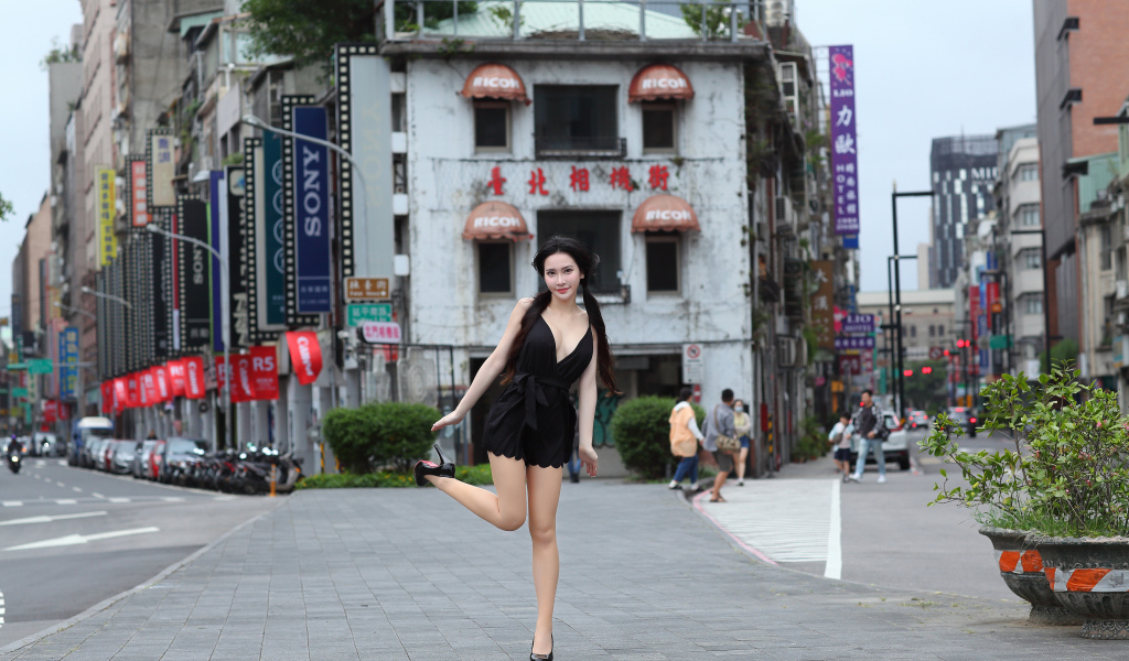 Девушка азиатка в черном платье стоит у дома