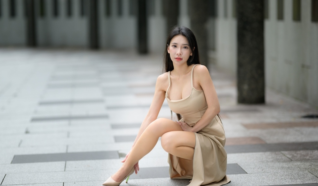 Девушка азиатка в платье сидит на корточках