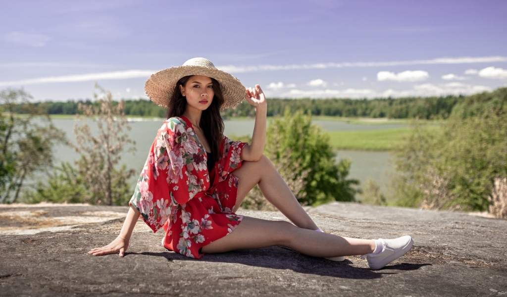 Девушка азиатка в шляпе лежит на камне