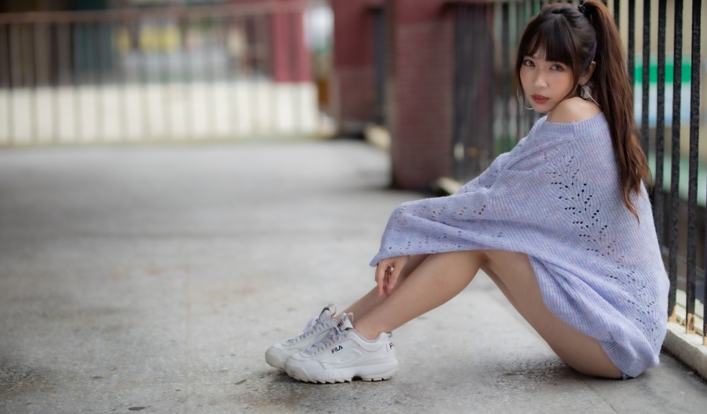 Девушка азиатка в свитере и белых кроссовках 