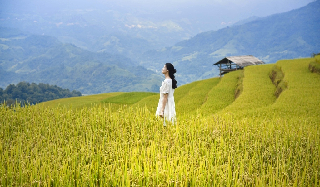 Девушка азиатка в белом платье дышит горным воздухом