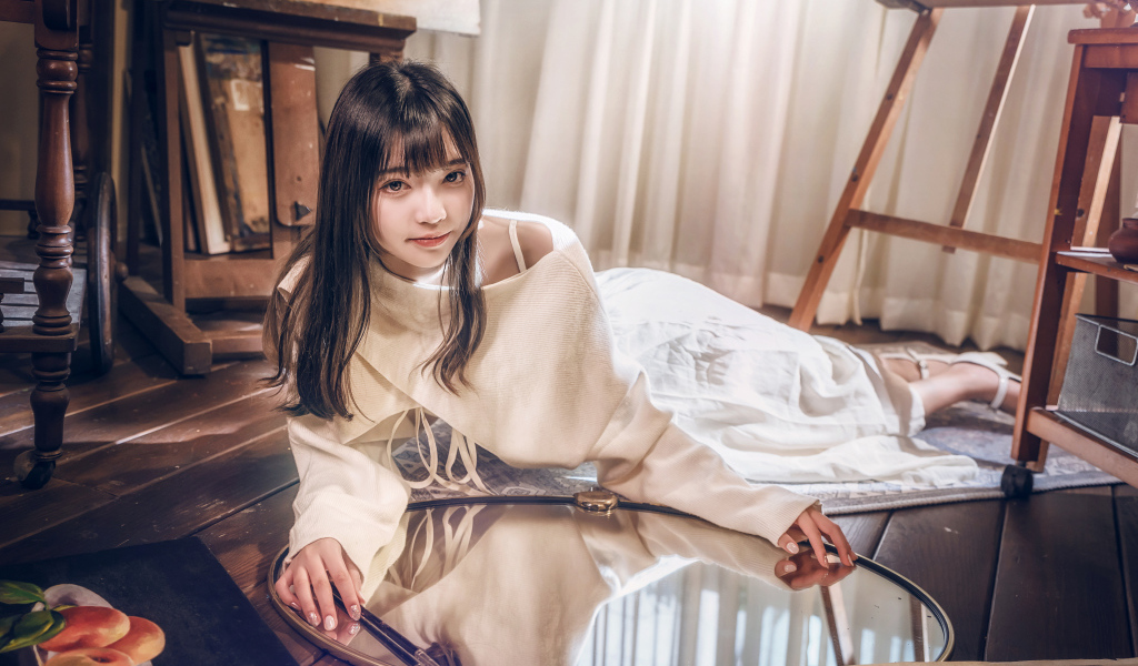 Девушка азиатка в белом платье лежит на полу