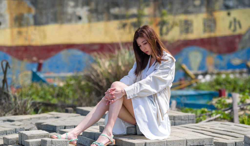 Девушка азиатка в белой рубашке сидит у воды