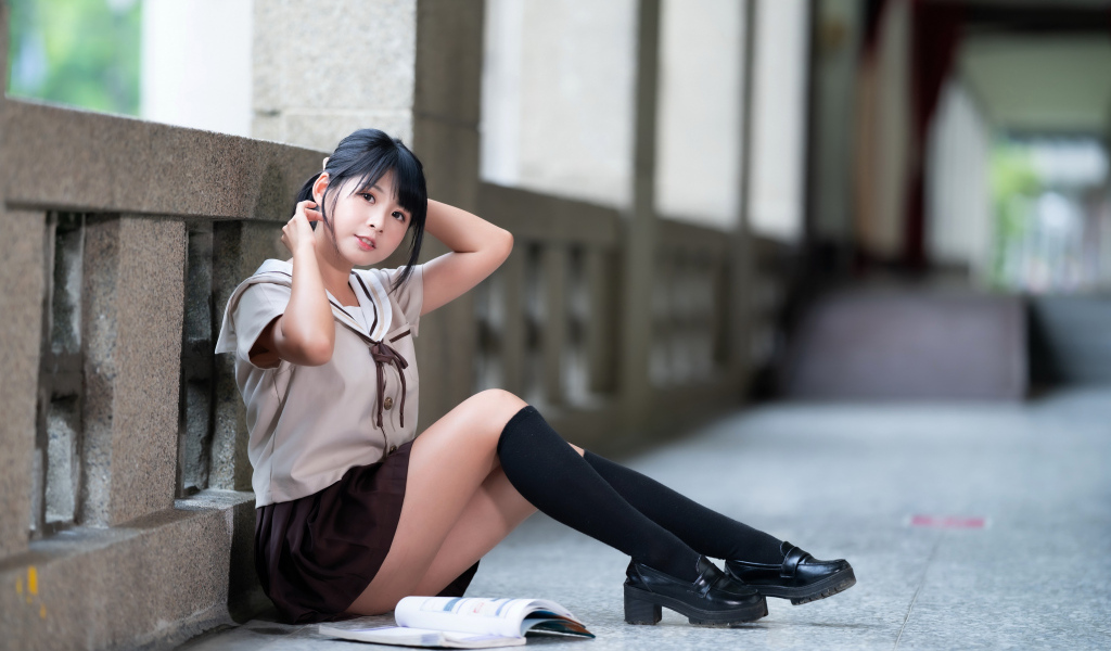 Девушка азиатка в школьной форме сидит на полу