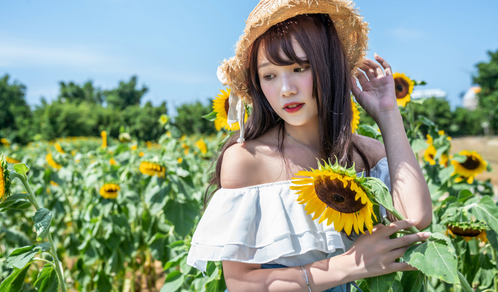Девушка азиатка на поле с подсолнухами