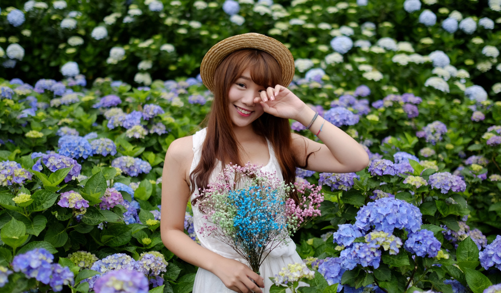 Девушка азиатка у куста с цветами гортензии