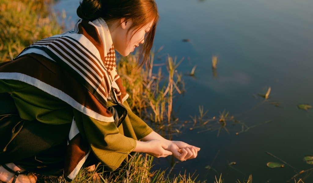 Девушка азиатка сидит у пруда