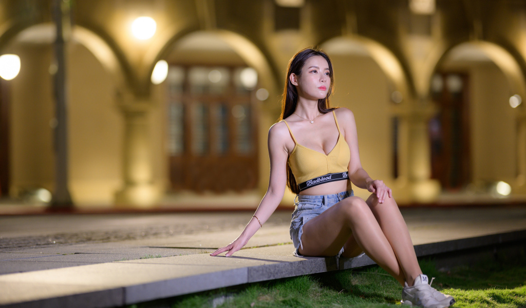 Девушка азиатка сидит на бетонной плите у дома