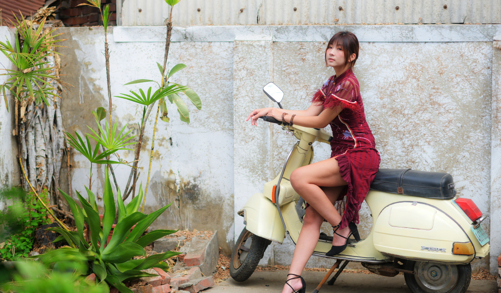 Asian girl sitting on a scooter against the wall