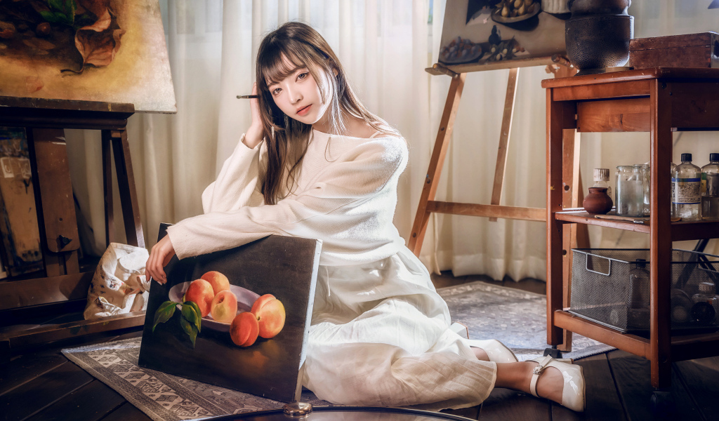 Девушка азиатка сидит с картиной на полу