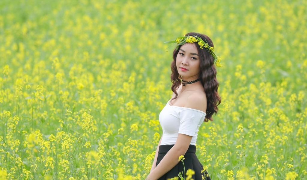Девушка азиатка стоит на рапсовом поле