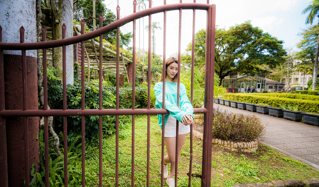 Девушка азиатка стоит у железных ворот 