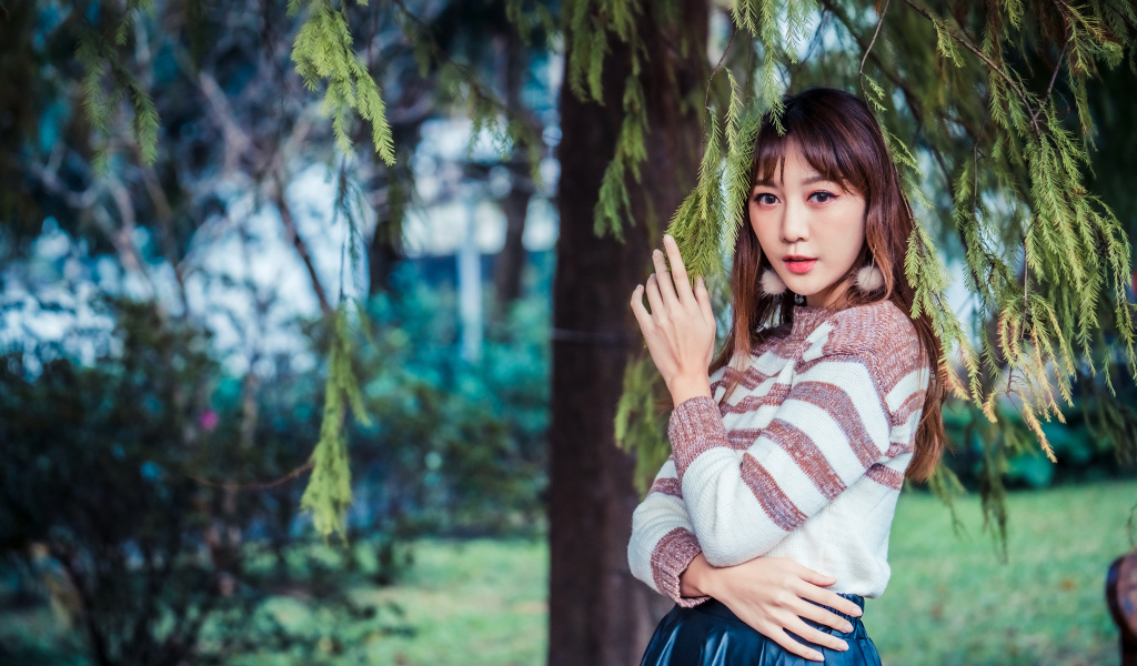 Девушка азиатка стоит у дерева ели