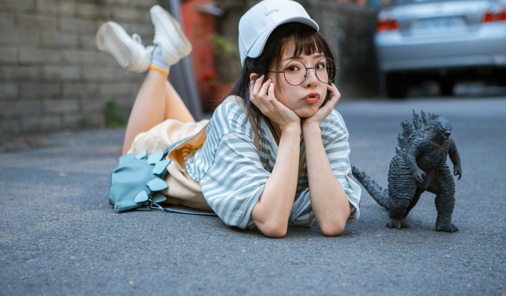 Девушка азиатка с фигуркой годзиллы