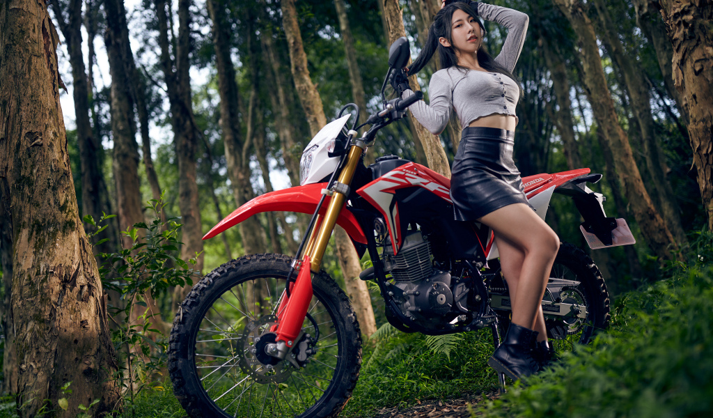 Девушка азиатка с мотоциклом в лесу