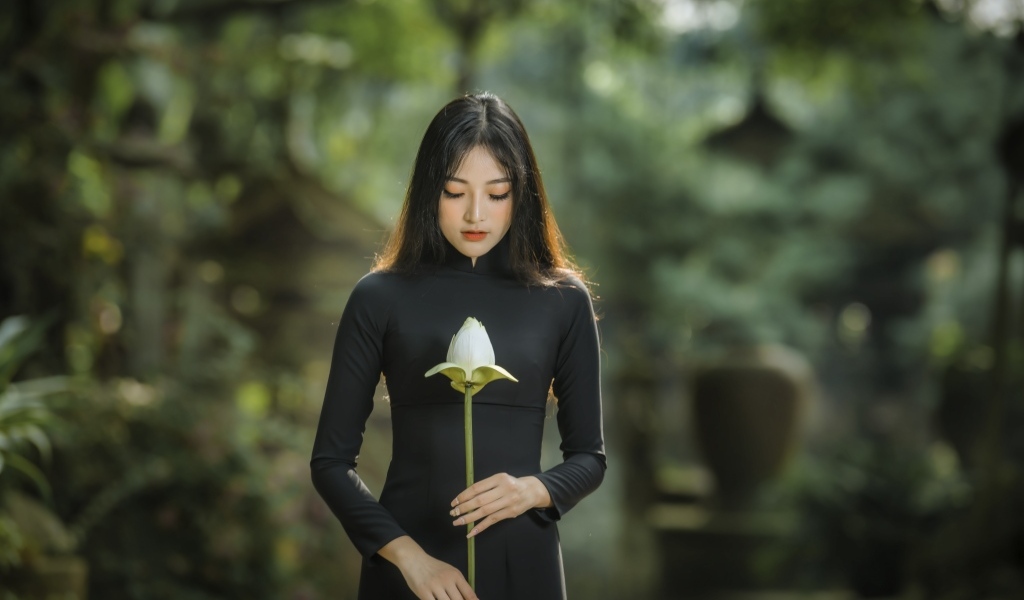 Красивая девушка азиатка в черном платье с цветком лотоса