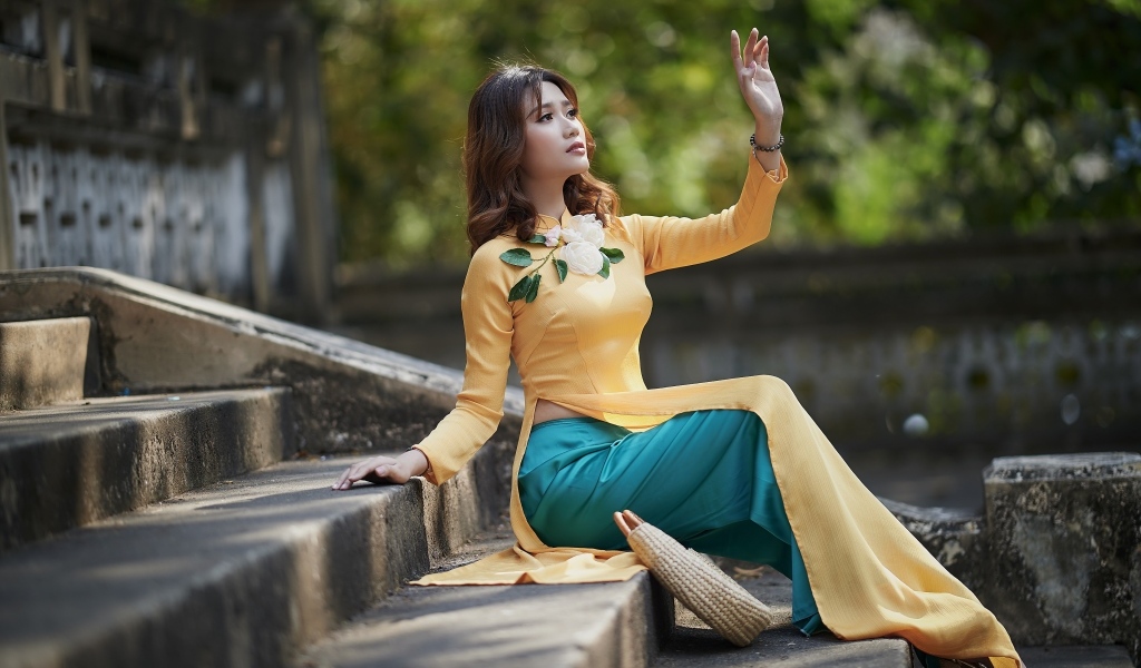 Красивая девушка азиатка сидит на ступеньках