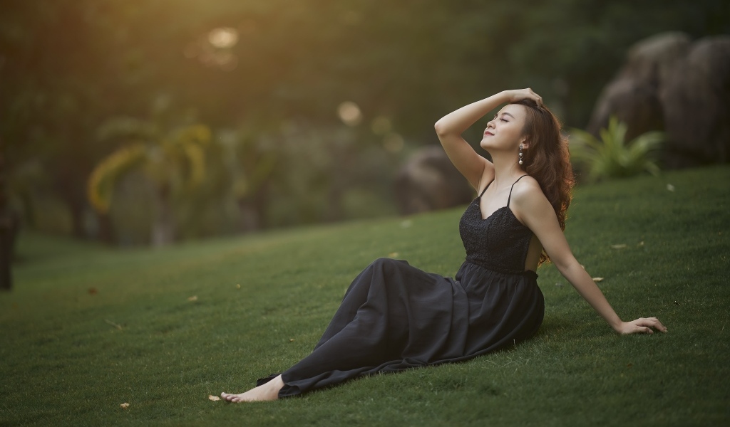 Красивая азиатка с закрытыми глазами в черном платье