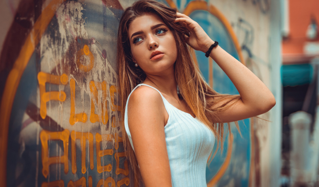 Красивая голубоглазая девушка стоит у стены