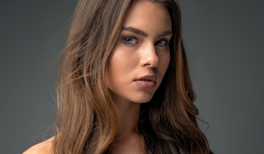 Красивая девушка шатенка на сером фоне 