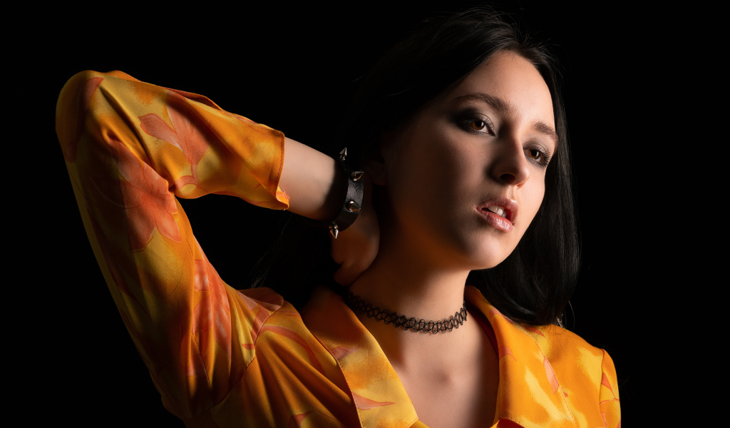 Красивая девушка шатенка с рукой в волосах на черном фоне