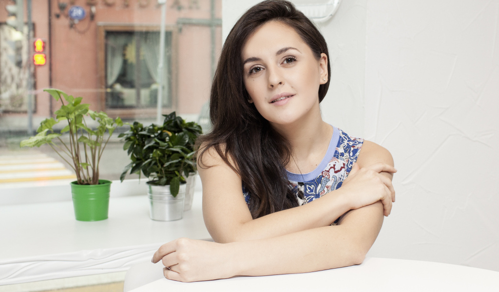 Красивая девушка брюнетка сидит за столиком в кафе 