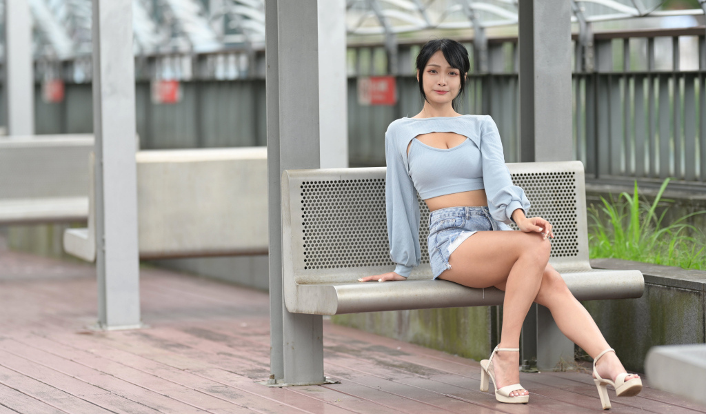 Красивая темноволосая девушка азиатка сидит на лавке