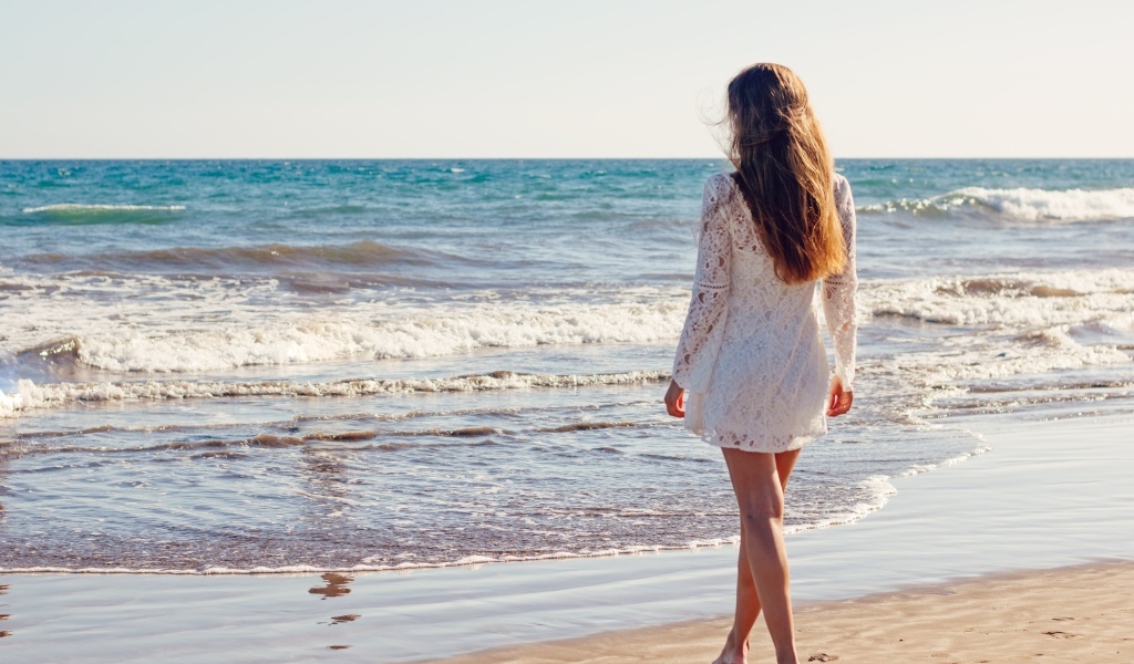 Красивая девушка в коротком белом платье на берегу моря
