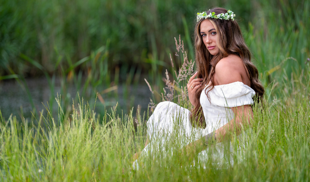 Красивая девушка в белом платье с венком на голове у пруда 