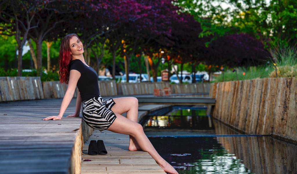 Красивая девушка опустила ноги в воду