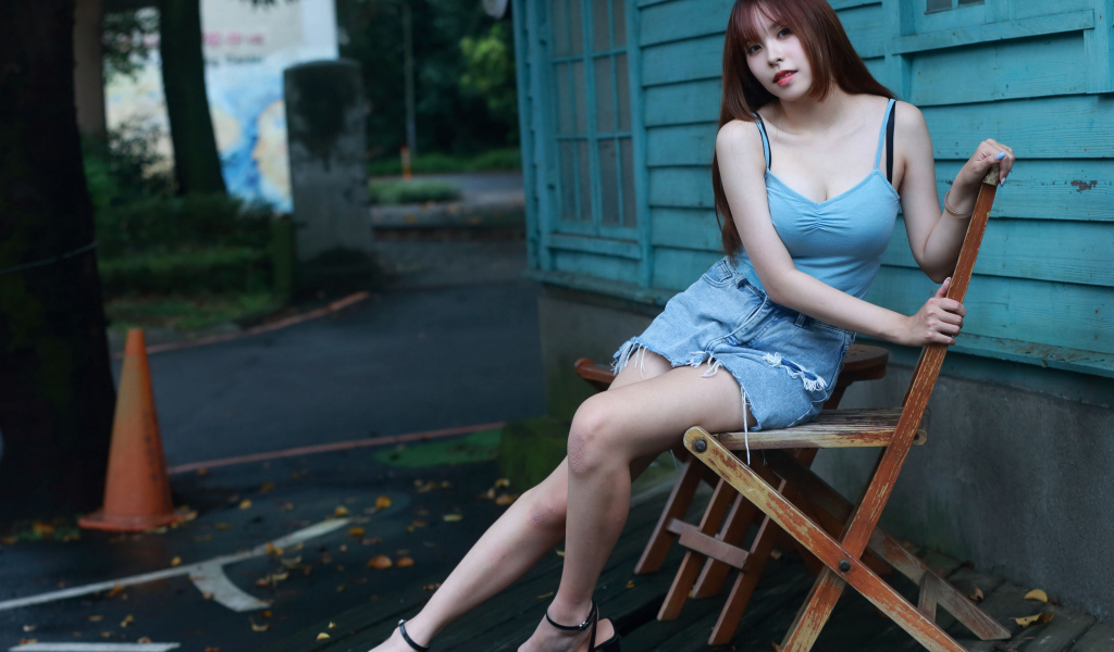 Красивая девушка сидит на стуле у дома