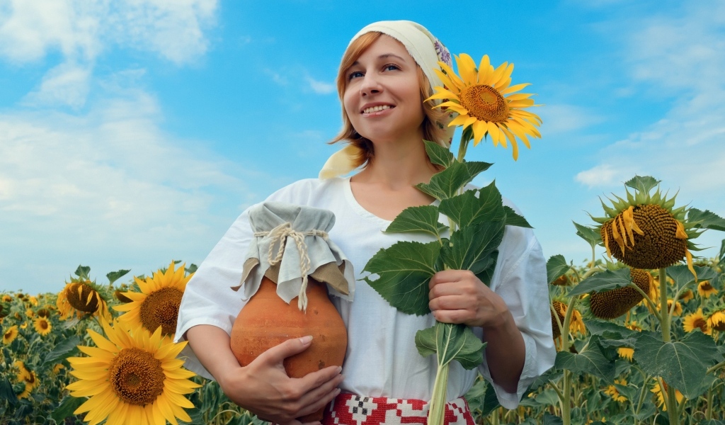 Красивая девушка с кувшином на поле с подсолнухами