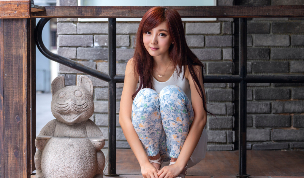 Милая девушка азиатка позирует со статуэткой