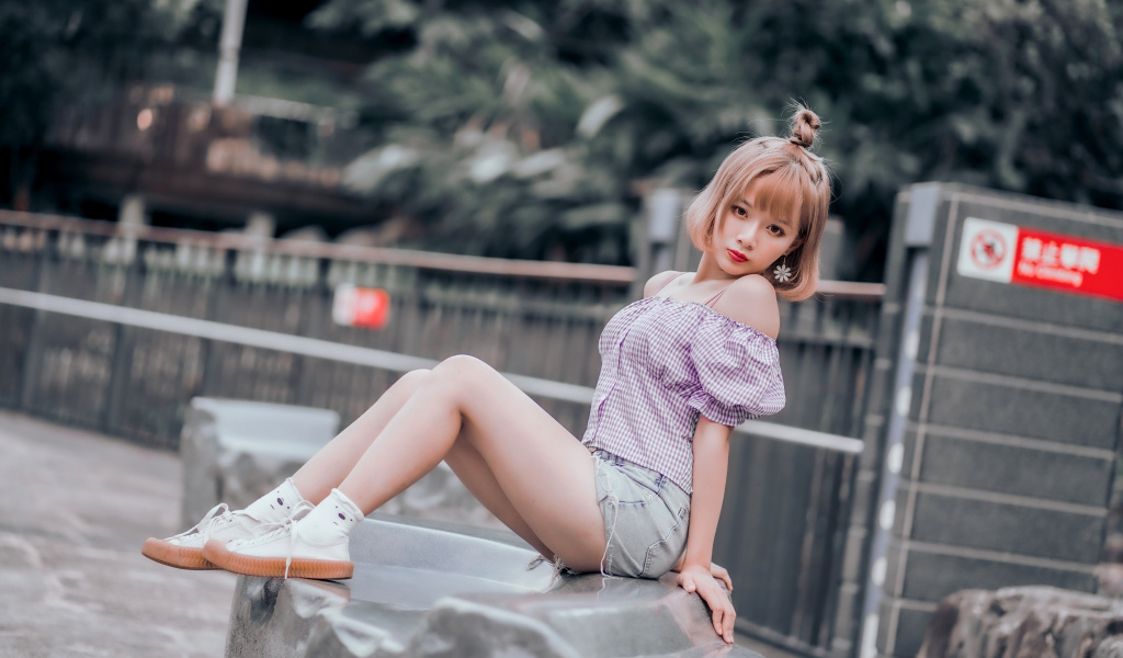 Милая девушка азиатка сидит на камне