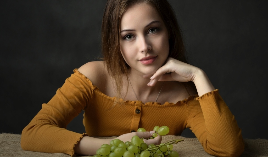 Милая шатенка ест белый виноград